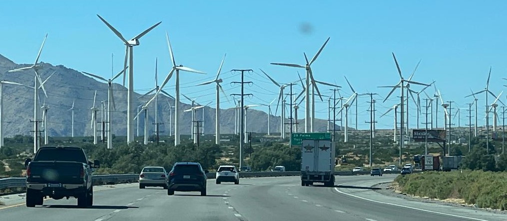 Cars driving on a highway with wind turbines

Description automatically generated