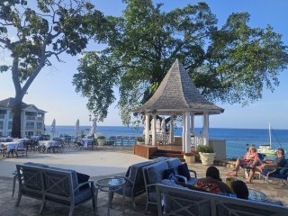 A group of people sitting on a patio by the water

Description automatically generated