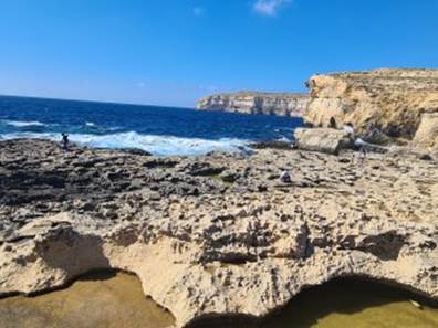 A rocky beach with a body of water in the background

Description automatically generated with medium confidence