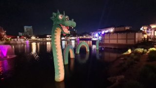 A large inflatable dragon in the water

Description automatically generated