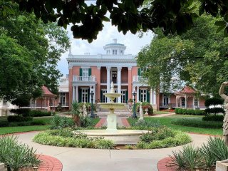 A large white house with a fountain in front of it

Description automatically generated with low confidence