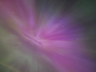 A purple and green light in the sky

Description automatically generated