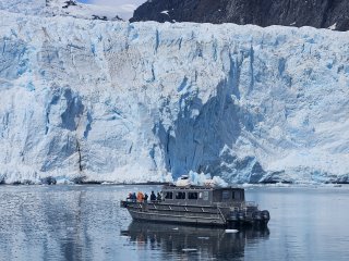 A boat in the water near a glacier

Description automatically generated