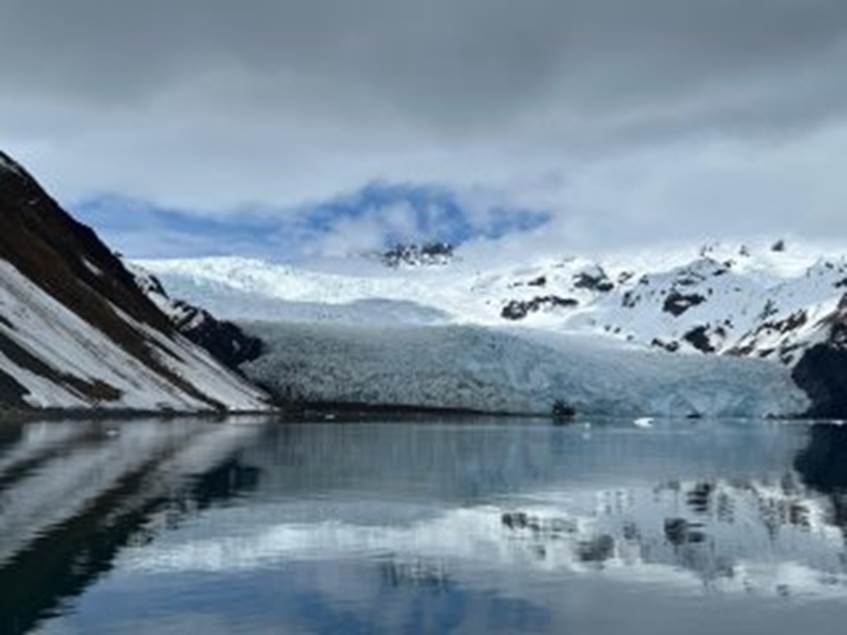 A lake with snow covered mountains and clouds

Description automatically generated