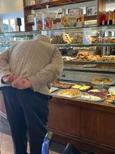 A person standing in front of a display of pastries

Description automatically generated with low confidence