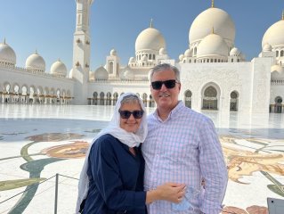 A person and person posing in front of a white building

Description automatically generated with medium confidence