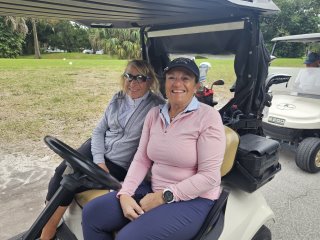 Two women sitting in a golf cart

Description automatically generated