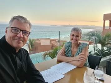 Two people sitting at a table with a view of the ocean and mountains in the

Description automatically generated with low confidence